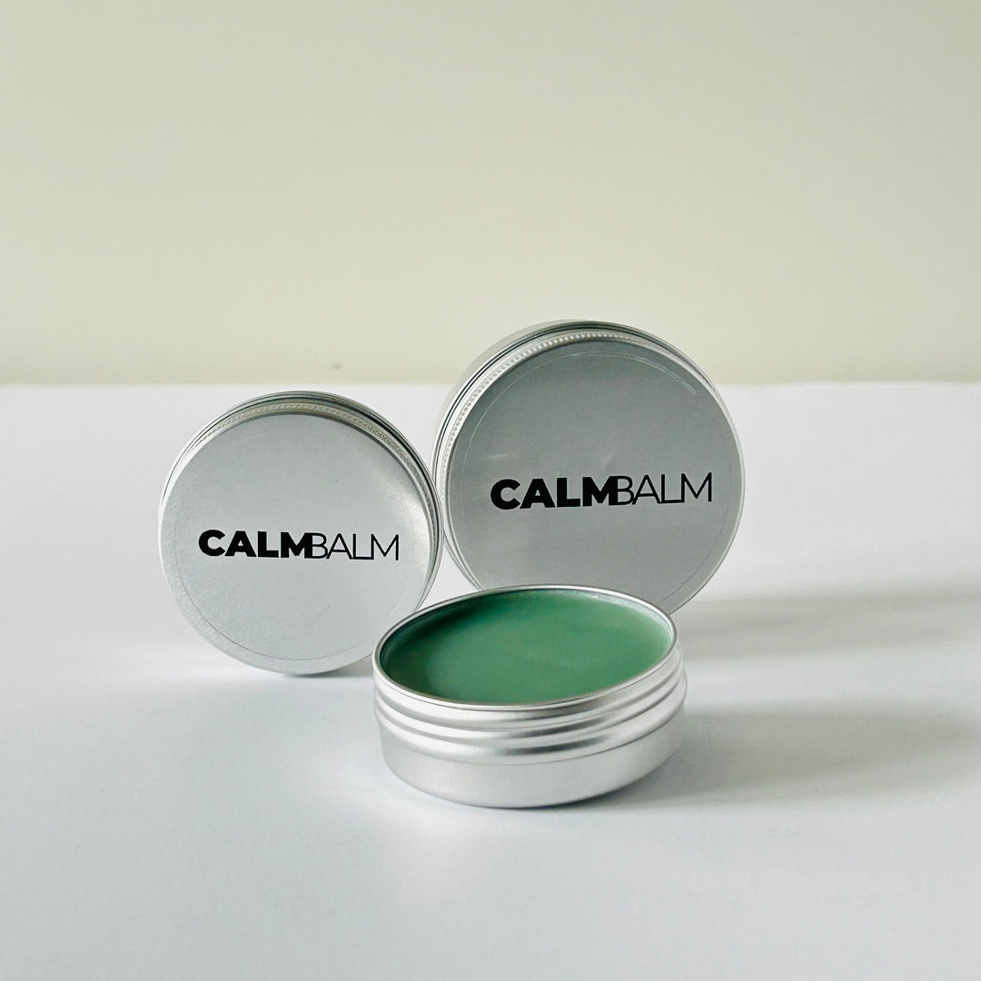 Two containers of Calm Balm with green balm inside on a white background