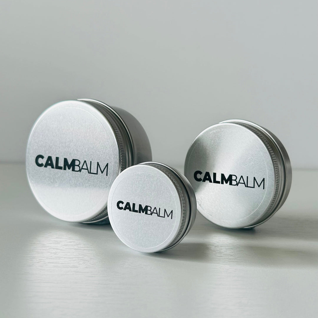 Three containers of Calm Balm on a light gray background