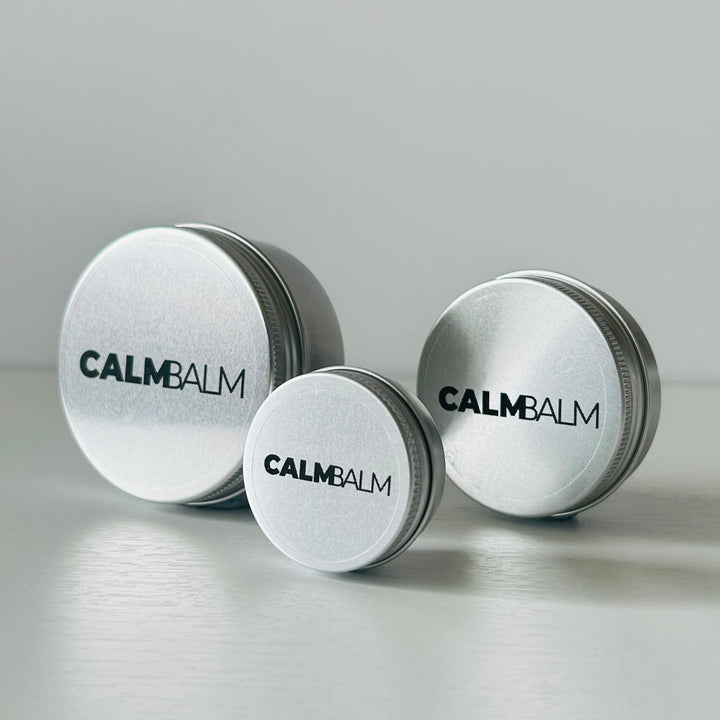 Three containers of Calm Balm on a light gray background