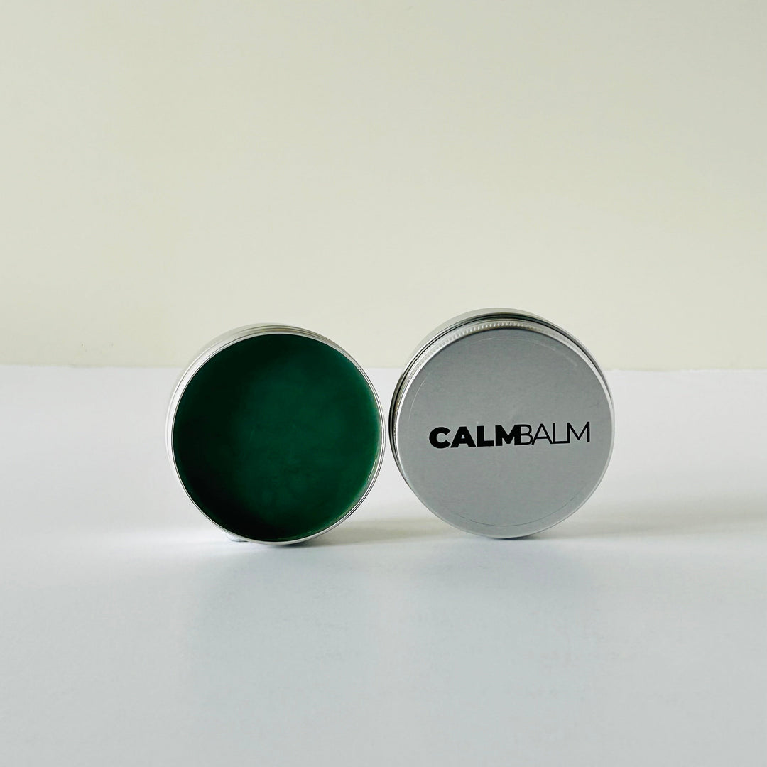 Container of Calm Balm with green balm inside on a white background