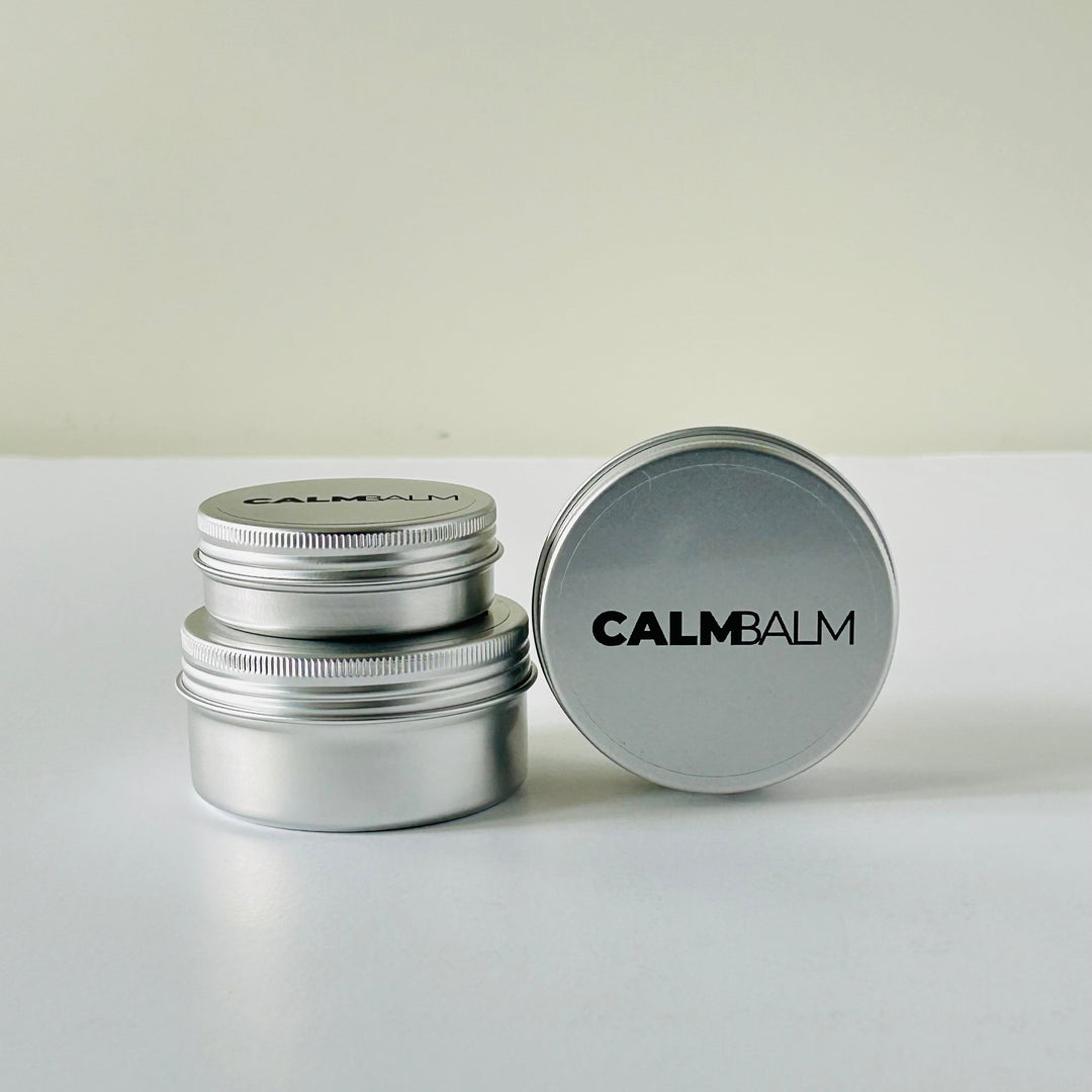 Silver metal container with 'CALMBALM' lid on a white background