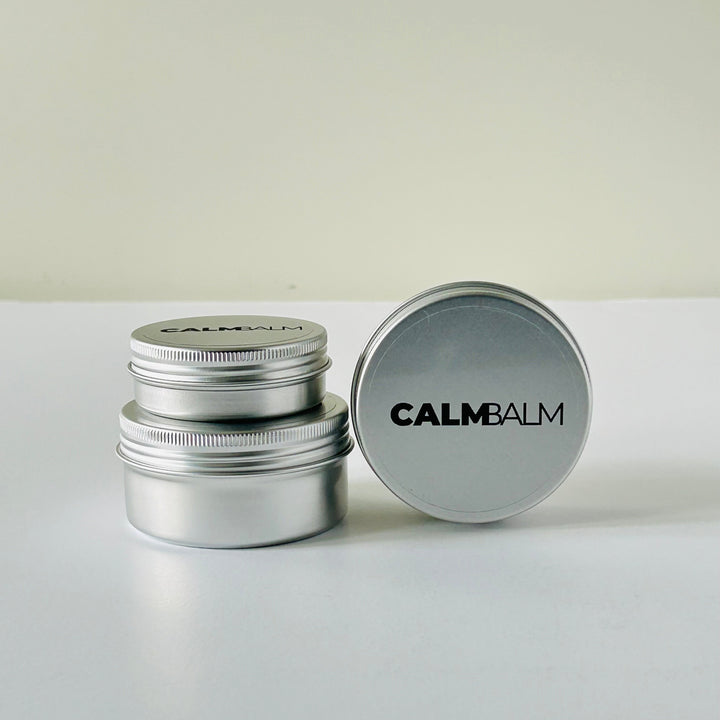 Silver metal container with 'CALMBALM' lid on a white background
