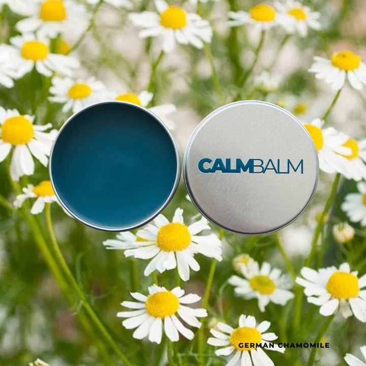 Calm Balm container with blue lid and 'Calm Balm' label on a field of daisies.