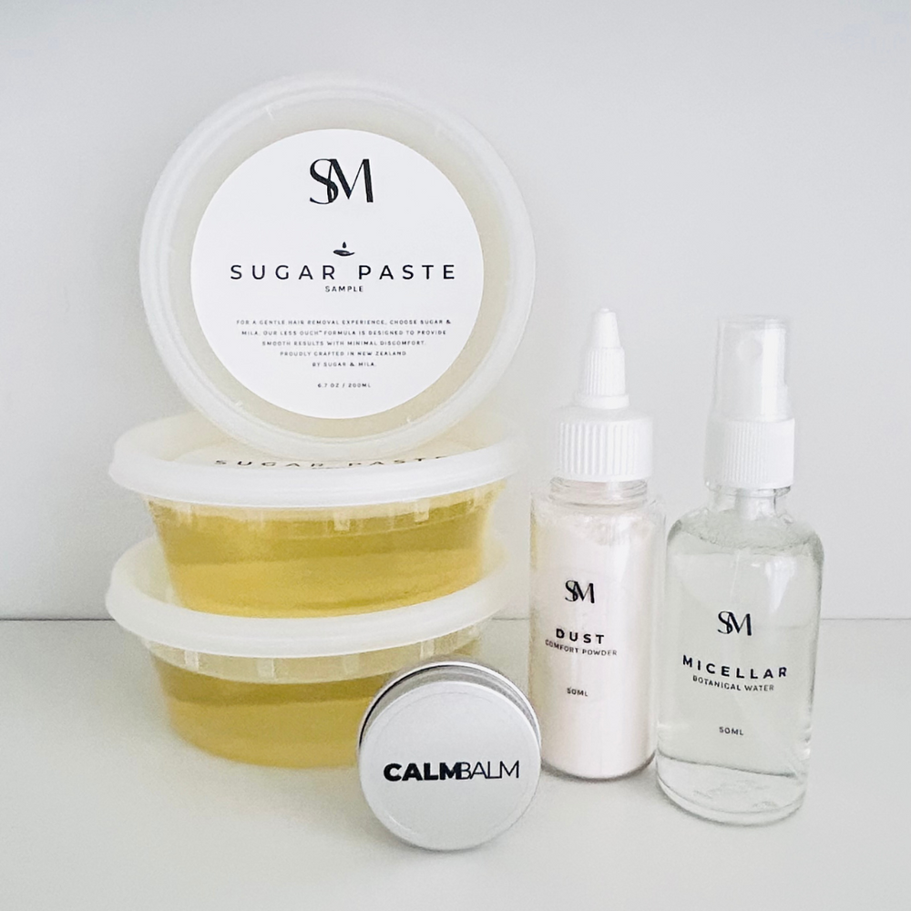 SM skincare products including a jar of sugar paste, bottles of dust and micellar water, and a round container of calm balm on a white background.