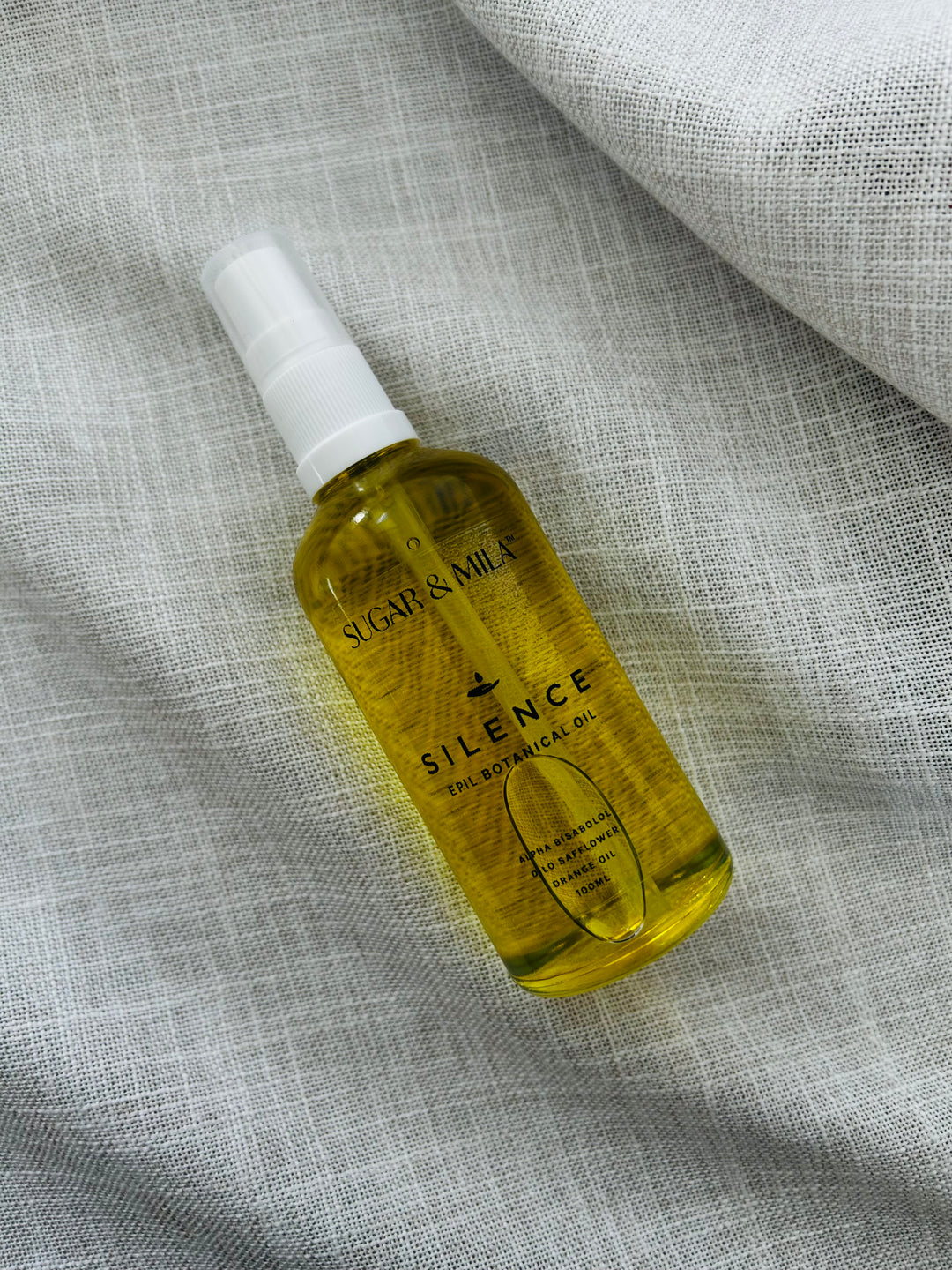 Bottle of Silence oil by Sugar & Milk on a textured gray fabric background