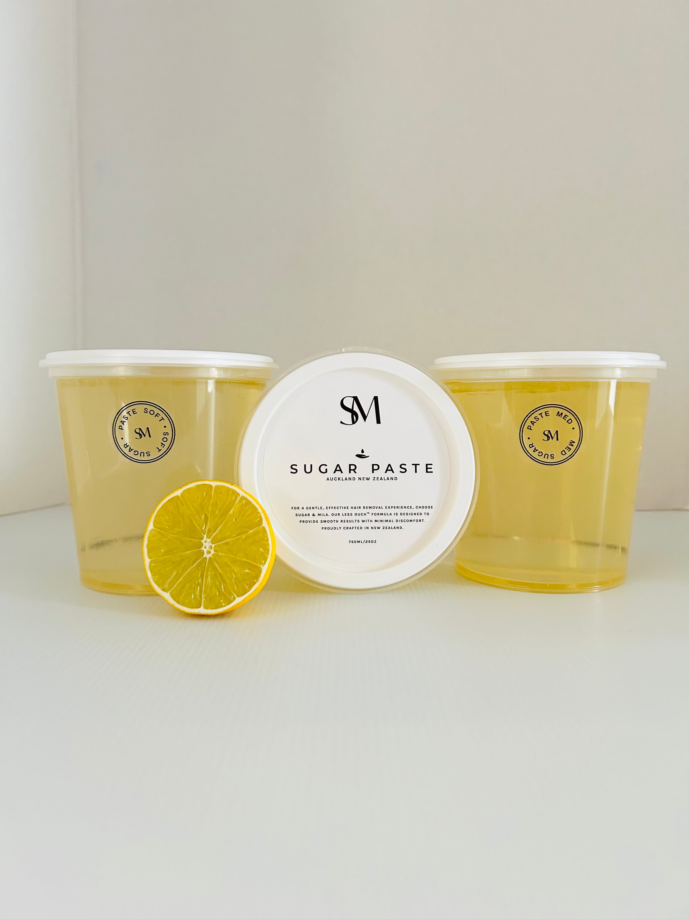 Three containers of sugar paste with a lemon wedge on a white surface
