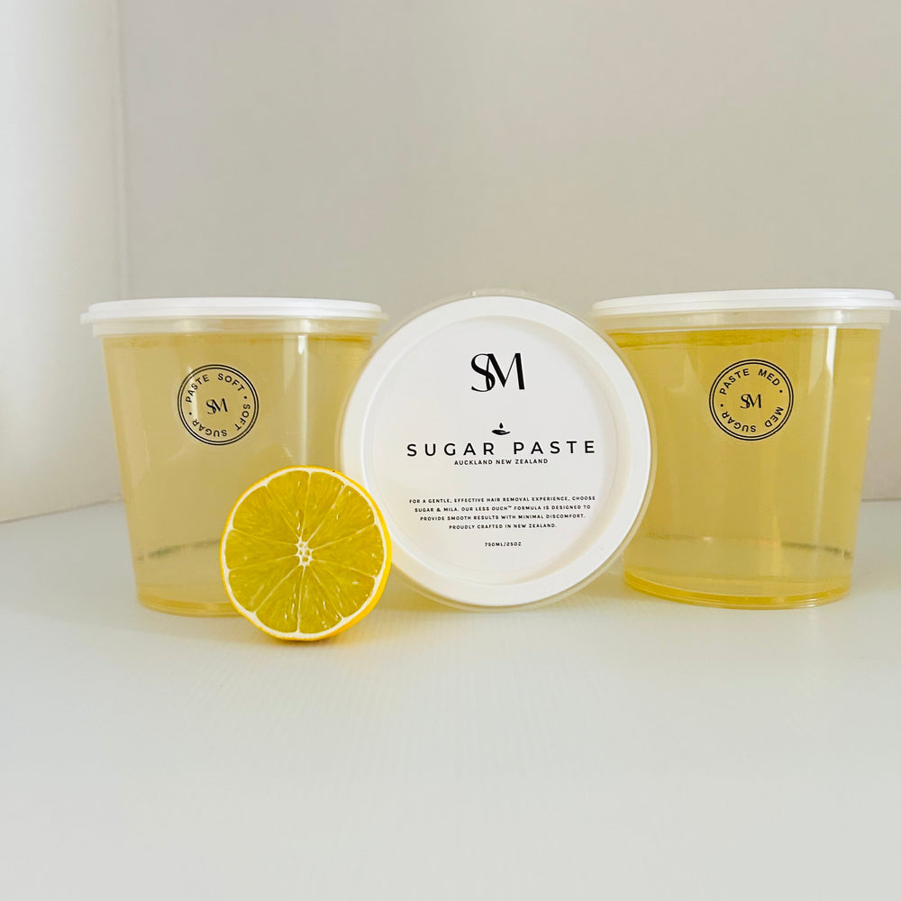 Two containers of sugar paste with a lemon wedge on a white surface