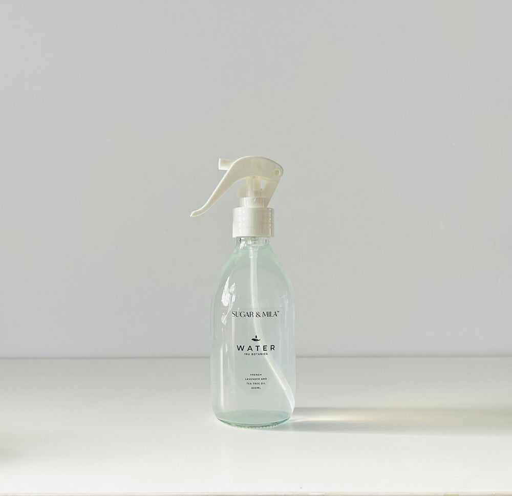 Clear spray bottle on a white surface with a neutral background
