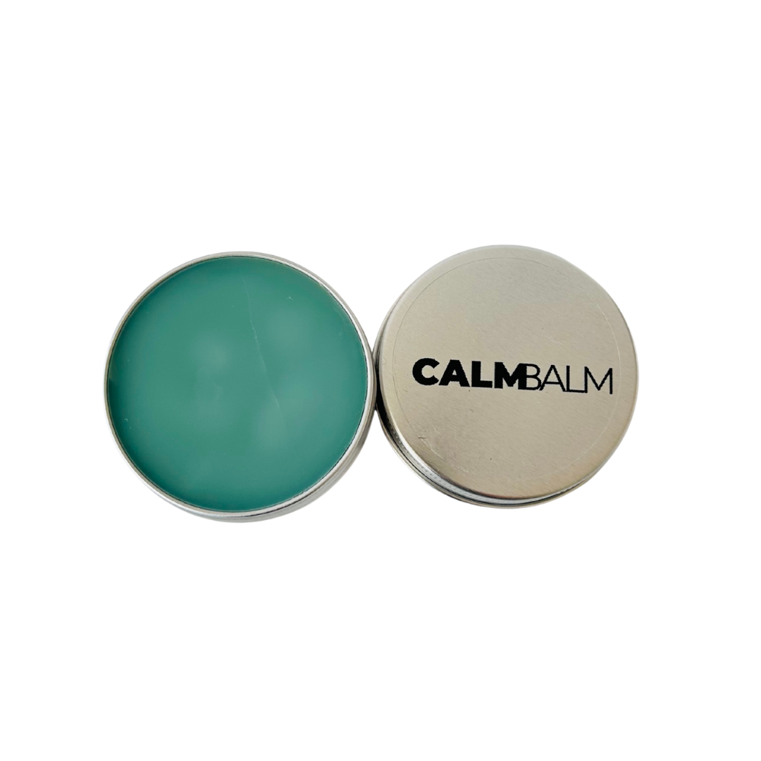 Green balm in a silver container with 'CALM BALM' lid on a white background